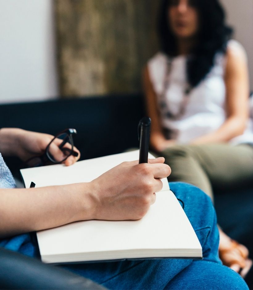 Sessão de psicoterapia: a psicóloga faz anotações em um caderno enquanto escuta a paciente